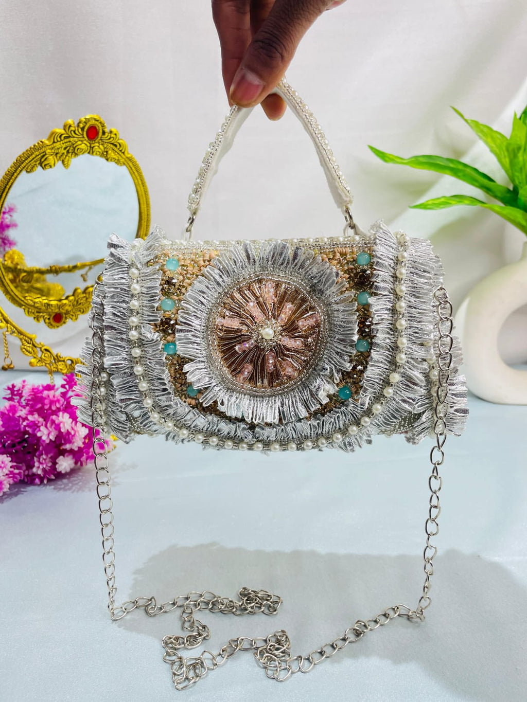 Noor medallion clutch held by its pearl-style handle with the detachable chain displayed below