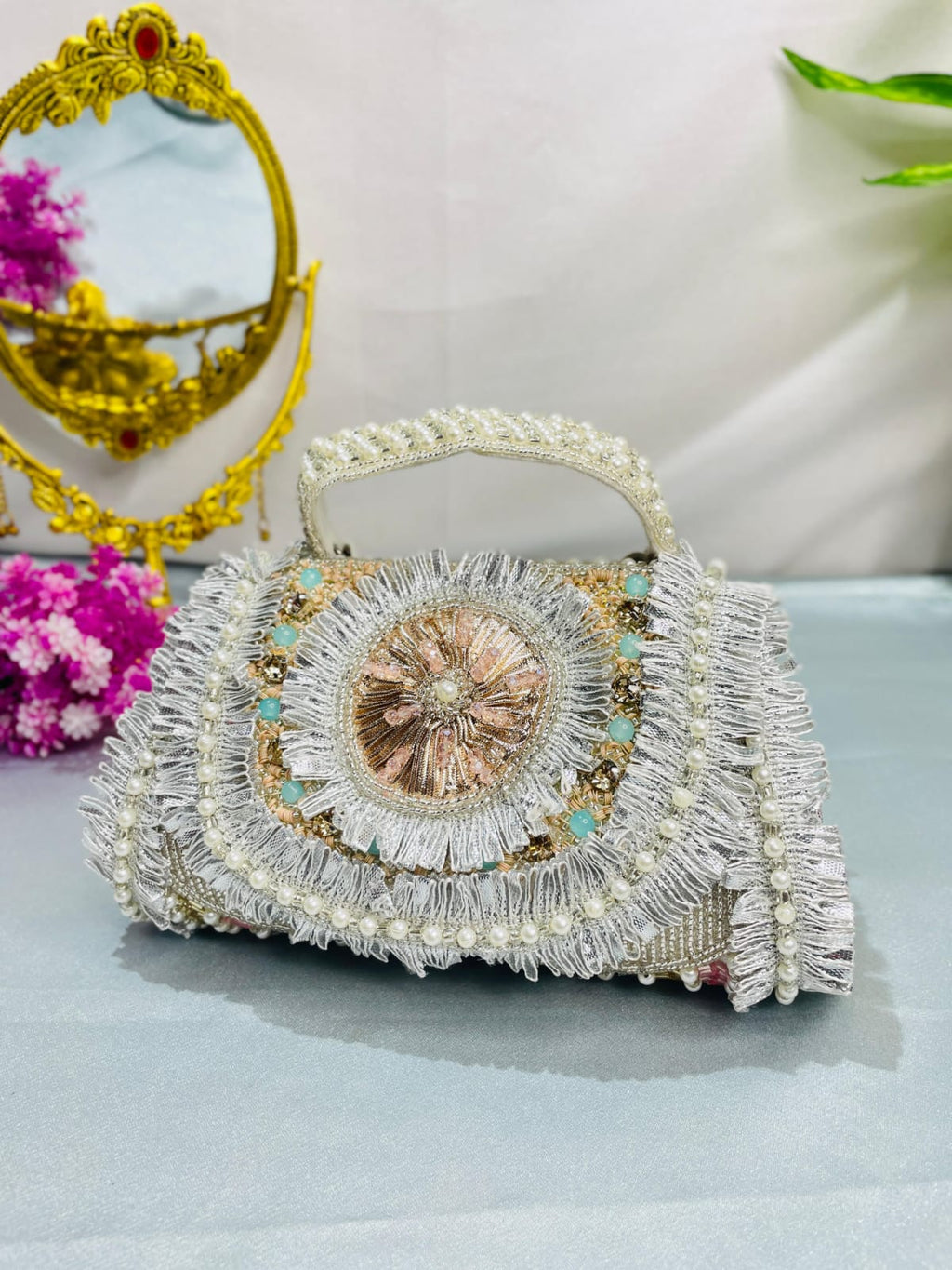 Angled front view of the Noor silver-tone medallion clutch and decorated handle