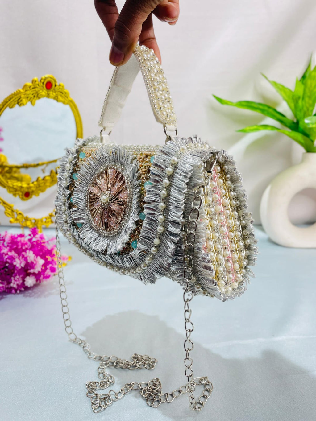 Side view of the Noor clutch showing its embellished side panel, handle and chain